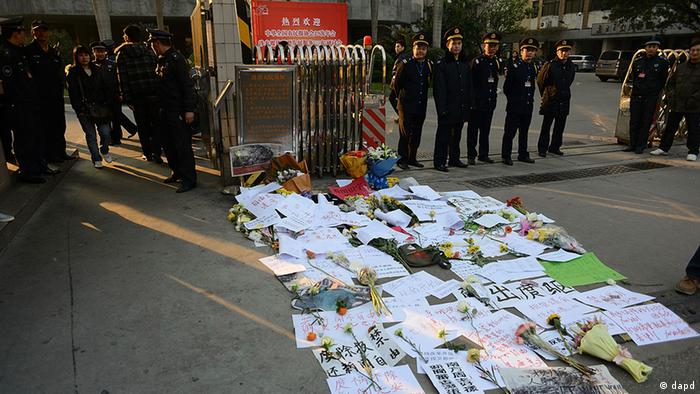 Security guards stand near protest banners and flowers are laid outside the headquarters of Southern Weekly newspaper in Guangzhou, Guangdong province Monday, Jan. 7, 2013. A dispute over censorship at the Chinese newspaper known for edgy reporting evolved Monday into a political challenge for China's new leadership as prominent scholars demanded a censor's dismissal and hundreds of protesters called for democratic reforms. (Foto:AP/dapd)