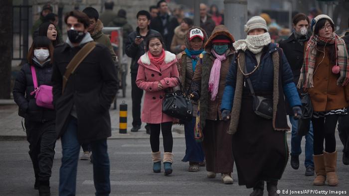 Pedestrians cross a street, some wearing face masks, during polluted weather in Beijing on January 13, 2013. Dense smog shrouded Beijing, with pollution at hazardous levels for a second day and residents advised to stay indoors, state media said. AFP PHOTO / Ed Jones (Photo credit should read Ed Jones/AFP/Getty Images) 