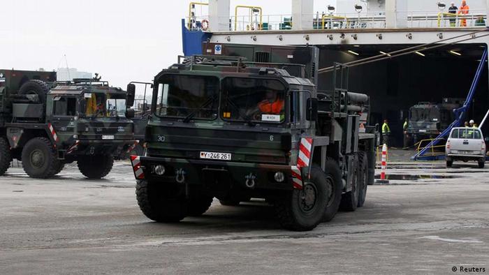 Green tanks roll across a parking lot after exiting the the large ship that carried them.
(Photo: REUTERS/Umit Bektas)
