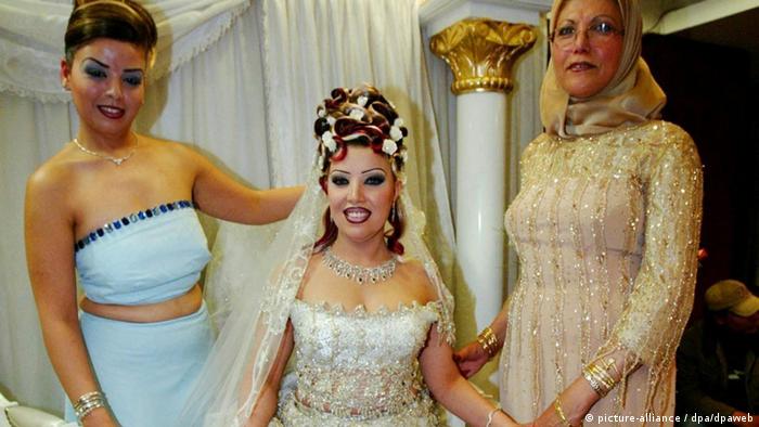 Tunesian bride in a white dress, or Kiswa stands between her mother and a bridesmaid. Foto: Mike Nelson dpa (zu dpa Korr: Hochzeit auf Tunesisch: Schwere Braut, laute Trommel und süßes Gebäck vom 08.04.2004)