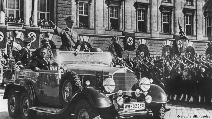 Hitler standing in his car, driving through crowds in Vienna