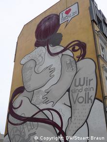 Graffiti in Berlin with two people embracing and the words I love Berlin and We are one people