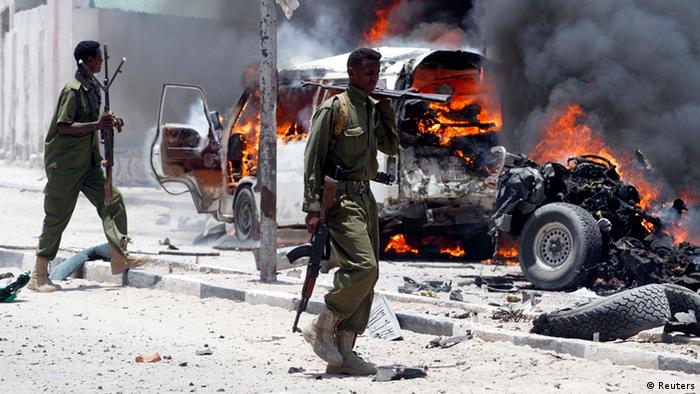 Policemen walk past the scene of an explosion near the presidential palace in Somalia's capital Mogadishu, March 18, 2013. A car bomb exploded near the presidential palace in the Somali capital Mogadishu on Monday, killing at least 10 people in a blast that appeared to target senior government officials, police said. REUTERS/Feisal Omar (SOMALIA - Tags: CIVIL UNREST CRIME LAW POLITICS)