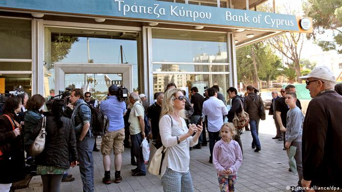 Customers and media representatives wait outside a branch of the Bank of Cyprus, in Nicosia, Cyprus, 28 March 2013 morning. All of the country's 26 banks were open from 12 pm until 6 pm (1000-1600 GMT) on 28 March with a withdrawal limit set at 300 euros (383 dollars) per person. Cyprus was braced for the reopening of its banks after nearly two weeks, after the government imposed tough capital controls for at least the next seven days. Police were going from bank to bank in central Nicosia to prevent problems, while dozens of people had started to queue in front of the banks' doors. EPA/KATIA CHRISTODOULOU