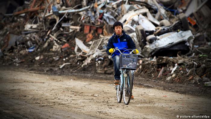 A young boy rides his bike trough the rubble in Ishinomaki, Miyagi Prefecture (Photo: EPA/STEPHEN MORRISON)