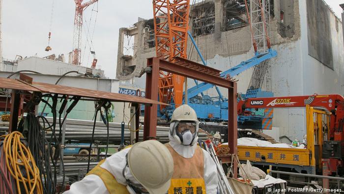 Workers of the Tokyo Electric Power Co (TEPCO) stand in front of the unit four reactor building (R) and unit three reactor building (L) of TEPCO's Fukushima Dai-Ichi nuclear power plant in Okuma Town, in Fukushima prefecture on March 1, 2013, . (Photo: JAPAN POOL/AFP/Getty Images) 