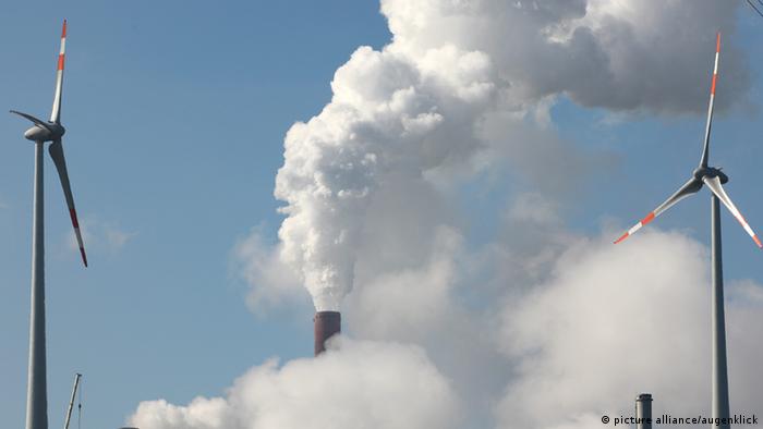 Fumes from a coal-fired power plant rise behind two wind turbines
(c) picture-alliance/augenklick