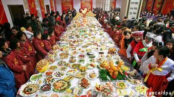 People look at dishes displayed on a large table during a dishes show event for the upcoming Chinese lunar New Year's Eve dinner in downtown Wuhan city, central China's Hubei province, 07 February 2010. More than 15,000 dishes were made by 9,048 families to celebrate the upcoming Chinese lunar New Year, also called Spring Festival which falls on 14 February, the first day of the 'Year of Tiger'. EPA/STR 