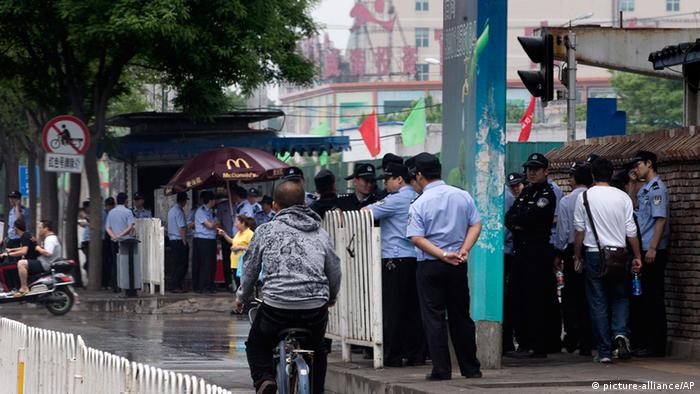 Chinese policemen stand guard on a pavement near a clothing wholesale mall where a woman fell to her death on May 3, in Beijing Thursday, May 9, 2013. With anti-riot vans and helmeted paramilitary forces, police in China's capital smothered a southern district for a second day Thursday after a protest by hundreds of migrant workers, underscoring the authorities’ sensitivity over unrest driven by anger over social inequality. (AP Photo/Andy Wong) 
