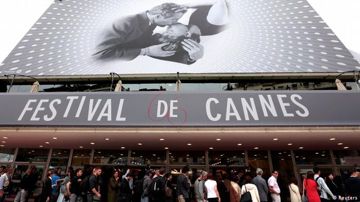 Visitors wait to enter in the Festival Palace covered by a giant canvas of the official poster of the 66th Cannes Film Festival in Cannes May 15, 2013. The 66th Cannes Film Festival will run from May 15 to May 26. REUTERS/Eric Gaillard (FRANCE - Tags: ENTERTAINMENT)