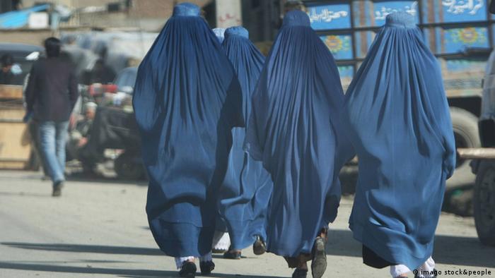 Tri žene u burkama hodaju ulicom, snimljene sleđa