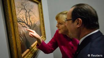 German Chancellor Angela Merkel draws the attention of French President Francois Hollande to a detail on the painting The Tree of Crows (Kraehen auf einem Baum) by Caspar David Friedrich as they visit the exhibition De l'Allemagne at the Louvre museum in Paris May 30, 2013. REUTERS/Bundesregierung/Steffen Kugler