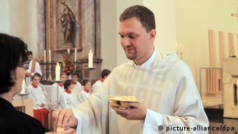 A priest hands out a piece of altar bread (photo: Marc Herwig dpa)