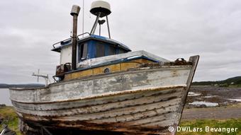 A moldy, disused fishing vessel sits on the ground.
(Photo: DW / Lars Bevanger)