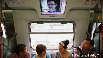 Passengers watch a television screen broadcasting news on Edward Snowden, a contractor at the National Security Agency (NSA), on a train in Hong Kong in this June 14, 2013 file photo. Snowden left Hong Kong on a flight for Moscow on June 23, 2013 and his final destination may be Ecuador or Iceland, the South China Morning Post said. REUTERS/Bobby Yip/Files (CHINA - Tags: POLITICS)
