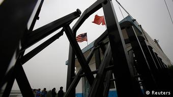 Flags belonging to the U.S. and China flutter through a closed gate at a factory where Chip Starnes, the co-owner of Coral Springs, is being held hostage, on the outskirts of Beijing, June 25, 2013. The American executive of a company producing speciality medical supplies in China said he has been detained by workers demanding severance packages since last Friday. REUTERS/Kim Kyung-Hoon (CHINA - Tags: SOCIETY CIVIL UNREST BUSINESS)