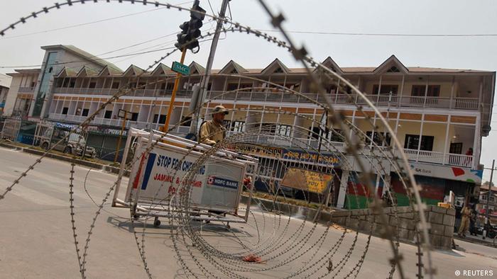 An Indian policeman stands guard behind concertina wire during a general strike in Srinagar June 25, 2013. (Photo: REUTERS/Danish Ismail)