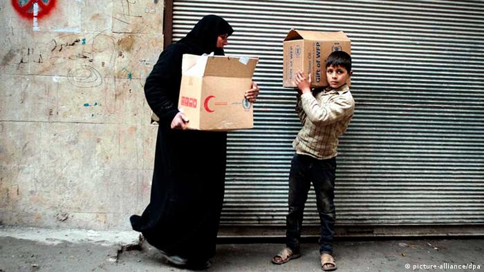 ARCHIV - Eine syrische Frau und ihr Sohn tragen Kartons mit Lebensmitteln am 19.02.2013 in Aleppo. Nach mehr als zwei Jahren Konflikt in Syrien fehlt es der Bevölkerung an allem. Hilfsorganisationen schlagen Alarm EPA/BRUNO GALLARDO (zu dpa «Syrien in Not - Lebensmittel immer knapper, heftige Kämpfe» vom 15.05.2013) +++(c) dpa - Bildfunk+++
