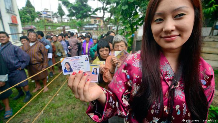epa03786581 A Bhutanese woman shows her voter ID card while standing in a queue along with others to cast her vote at Bangtsho polling station in Deothang constituency, Samdrupjongkhar district, Bhutan, 13 July 2013. Tens of thousands of people in Bhutan voted 13 July in the second-ever parliamentary elections, which are being seen as a verdict on five years of democracy in the tiny Himalayan nation. EPA/STRINGER
