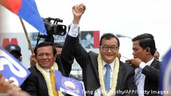 Cambodian opposition leader of the Cambodia National Rescue Party (CNRP) Sam Rainsy (C) raises his arm with Kem Sokha (centre L) Vice president of the CNRP as they greet supporters along a street in Phnom Penh on July 19, 2013 (Photo: AFP)
