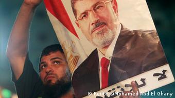 A supporter of deposed Egyptian President Mohamed Mursi carries a Mursi poster during a protest at the Rabaa Adawiya square, where Mursi supporters are camping, in Cairo July 27, 2013. At least 70 people died on Saturday after security forces attacked supporters of deposed President Mohamed Mursi in Cairo, Muslim Brotherhood spokesman Gehad El-Haddad said, adding the toll could be much higher. REUTERS/Mohamed Abd El Ghany (EGYPT - Tags: POLITICS CIVIL UNREST)