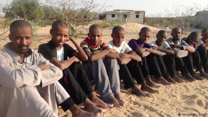 Several men who are refugees in the Sinai are seated on the ground .