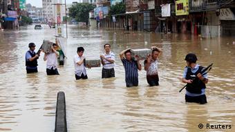 People carrying cash boxes walk across a flooded street (photo: REUTERS/Stringer)