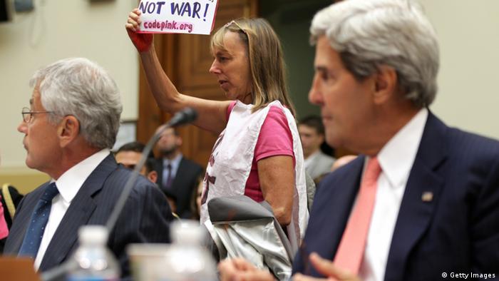 WASHINGTON, DC - SEPTEMBER 04: Medea Benjamin (C) of CodePink protests as U.S. Secretary of State John Kerry (R) and Defense Secretary Chuck Hagel testify during a hearing on Syria: Weighing the Obama Administration's Response before the House Foreign Affairs Committee September 4, 2013 on Capitol Hill in Washington, DC. Meanwhile, the Senate Foreign Relations Committee is considering a resolution drafted by committee chairman Sen. Robert Menendez (D-NJ) and ranking member Sen. Bob Corker (R-TN) to authorize military against the Bashar al-Assad regime that can be voted on as early as today. (Photo by Alex Wong/Getty Images)