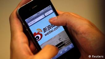 A man holds an iPhone as he visits Sina's Weibo microblogging site in Shanghai in this May 29, 2012 file photo. Sina Corp, one of China's biggest Internet firms, runs the microblogging site, which has 500 million registered users. It also employs the censors. The Sina Weibo censors are a small part of the tens of thousands of censors employed in China to control content in traditional media and on the Internet. Picture taken May 29, 2012. REUTERS/Carlos Barria/Files (CHINAMEDIA - Tags: MEDIA BUSINESS TELECOMS)