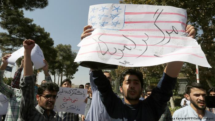  Iranian supporters of the Basiji militia raise up anti-US placards as Iranian president Hassan Rouhani's motorcade leaves Tehran's Mehrabad Airport upon his arrival from New York, on September 28, 2013. Some 60 hardline Islamists chanted 'Death to America' and 'Death to Israel' but they were outnumbered by 200 to 300 supporters of the president who shouted: 'Thank you Rouhani.' AFP PHOTO/ATTA KENARE (Photo credit should read ATTA KENARE/AFP/Getty Images) 