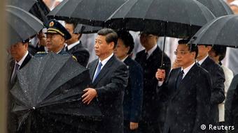 China's President Xi Jinping takes down his umbrella next to Premier Li Keqiang (R) before they and other Chinese Communist Party top leaders stand in silent tribute as it rains during a tribute ceremony at the Monument to the People's Heroes, on the 64th anniversary of the founding of the People's Republic of China, in Beijing October 1, 2013. China celebrates its National Day on Tuesday. REUTERS/Jason Lee (CHINA - Tags: POLITICS ANNIVERSARY)
