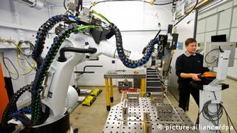 Ein Mitarbeiter stellt am 15.10.2013 in Ditzingen (Baden-Württemberg) beim Maschinenbauer Trumpf eine Roboterzelle ein. Das Familienunternehmen Trumpf kauft einen chinesischen Werkzeugmaschinenhersteller. Foto: Daniel Bockwoldt/dpa +++(c) dpa - Bildfunk+++