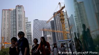 Women walk past a construction site and office buildings at the Central Business District during their lunch break in Beijing, China Tuesday, Oct. 8, 2013. Chinese President Xi Jinping sought Monday to reassure Asian business and political leaders that his country only aspires to peace and that he is confident its economic growth will remain robust despite a recent slowdown. (AP Photo/Andy Wong) 