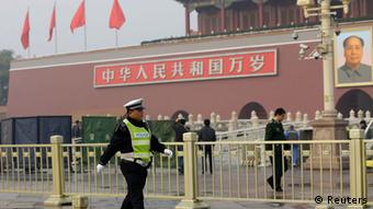 A policeman walks past in front of the giant portrait of the late Chinese Chairman Mao Zedong as other policemen clean up after a car accident at the Tiananmen Square in Beijing, October 28, 2013. Chinese police on Monday evacuated Beijing's Tiananmen Square, the site of 1989 pro-democracy protests bloodily suppressed by the government, following a fire after a car ran into a crowd, a Reuters witness and state media said. REUTERS/Jason Lee (CHINA - Tags: SOCIETY POLITICS)