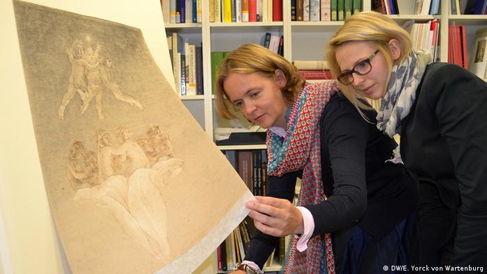 An artwork is in focus at the front, left of the photo as researchers Britta Olényi (left) and Jasmin Hartmann investigate the piece Photo: DW/Elisabeth Yorck von Wartenburg