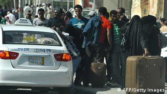 Foreign workers wait for a taxi as they leave Manfuha
(Photo: FAYEZ NURELDINE/AFP/Getty Images)