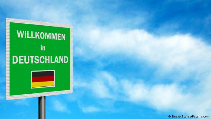 Himmel und Schild mit der Aufschrift „Willkommen in Deutschland“.