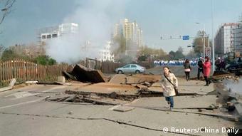 A woman runs on a damaged street after a pipeline explosion in Huangdao, Qingdao, Shandong Province November 22, 2013. According to Xinhua News Agency, the pipeline blast occurred early Friday morning which resulted in an oil leakage, killed at least six people and left seven severely injured. REUTERS/China Daily (CHINA - Tags: DISASTER ENERGY TPX IMAGES OF THE DAY) CHINA OUT. NO COMMERCIAL OR EDITORIAL SALES IN CHINA