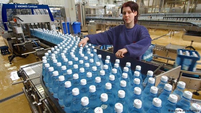 Eine Technikerin kontrolliert Flaschen auf einem Fließband. (Photo: Wolfgang Thieme) 