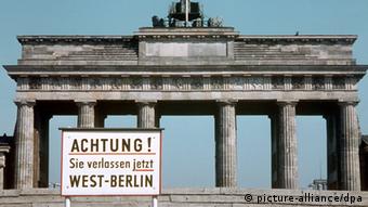 A sign is placed in front of the large stone Brandenburg Gate.