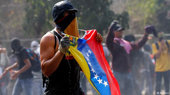A protesters with his face covered holds a Venezuelan flag
(Foto: Carlos Garcia Rawlins/REUTERS)