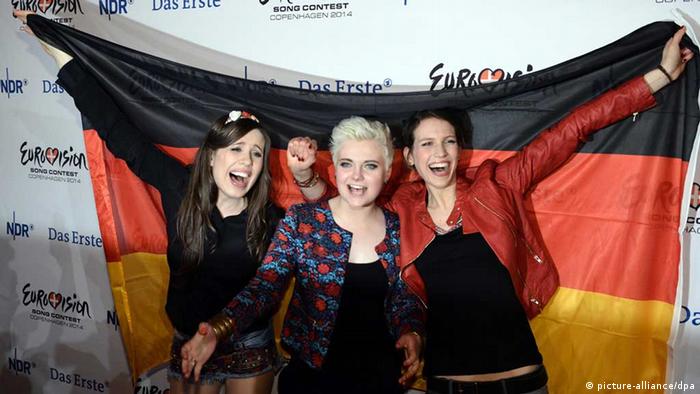 The three mmebers of Elaiza holding a German flag behind them