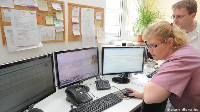 Медсестра Центра телемедицины в Бранденбурге, контролирующая показатели пациентов на трех компьютерных мониторах одновременно