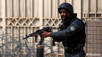 An Afghan policeman takes position near an election commission office during an attack by gunmen in Kabul March 29, 2014. 
