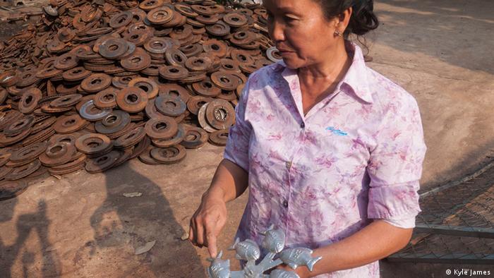 Lao Fun, who helps run a metal workshop, shows off the iron fish that she makes (photo: Kyle James)