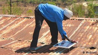 A picture of a man installing a solar panel on a roof