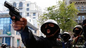Одетый в маску и каску молодой человек держит пистолет во время столкновений 2 мая в Одессе
