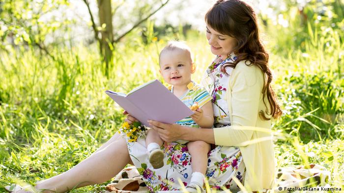 Symbolbild Mutter mit Baby Buch lesen vorlesen Natur 