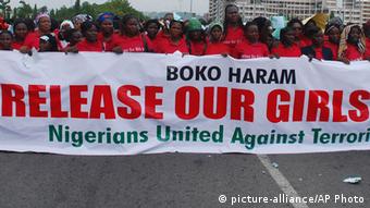 A bringbackourgirls protest in Nigeria with demonstratots holding a banner and dressed in red 