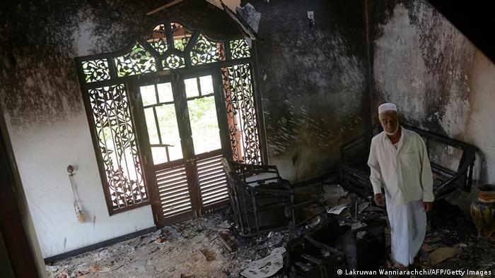 A Sri Lankan resident surveys the damage to a charred Muslim-owned home following clashes between Muslims and an extremist Buddhist group in the town of Alutgama on June 17, 2014.